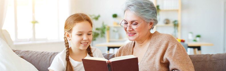 child and older adult reading book