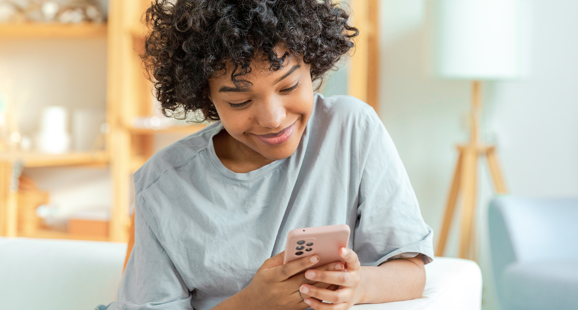 closeup photo of person smiling and looking at mobile phone