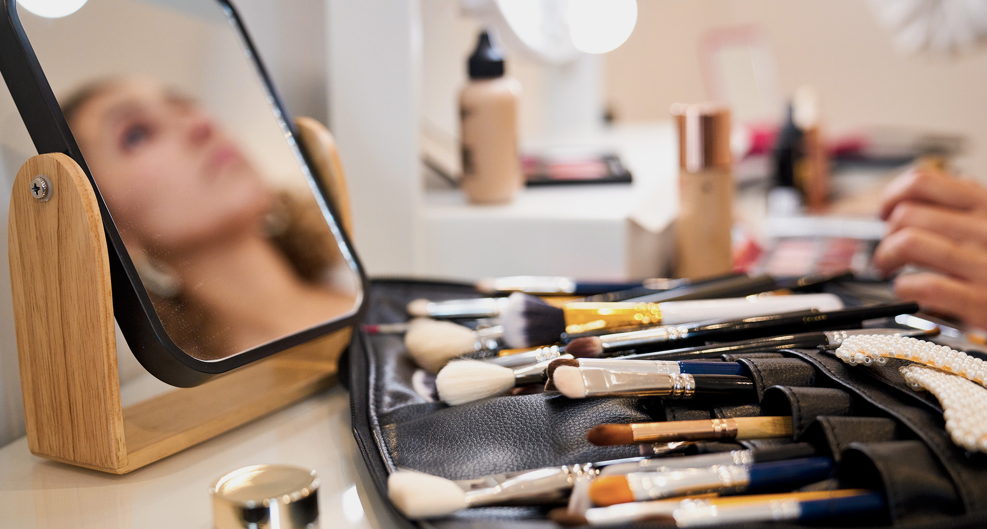 makeup brushes in leather pouch on table with small mirror