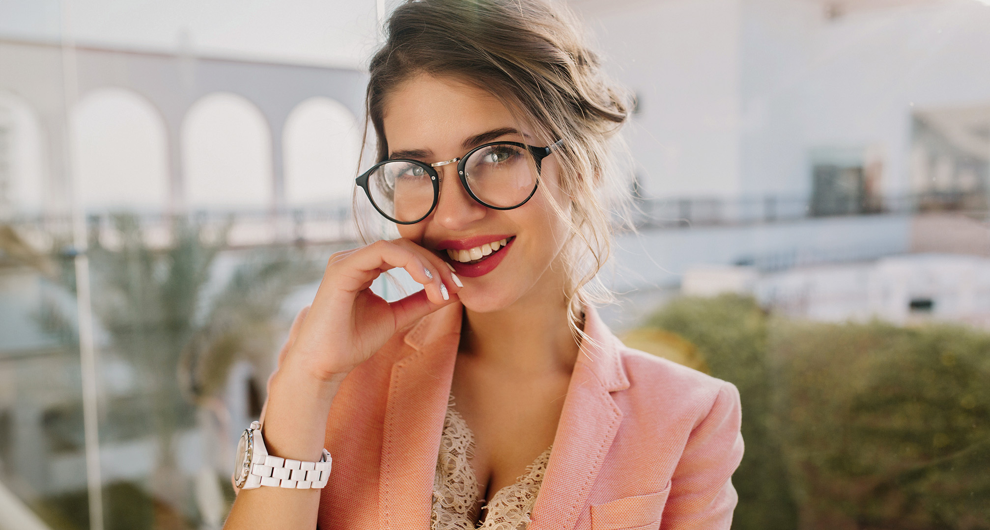 person with red lipstick wearing black glasses frames and pink blazer jacket
