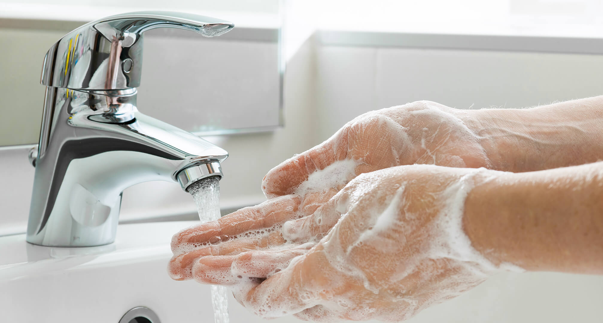 Seife wird von Händen im Waschbecken abgespült