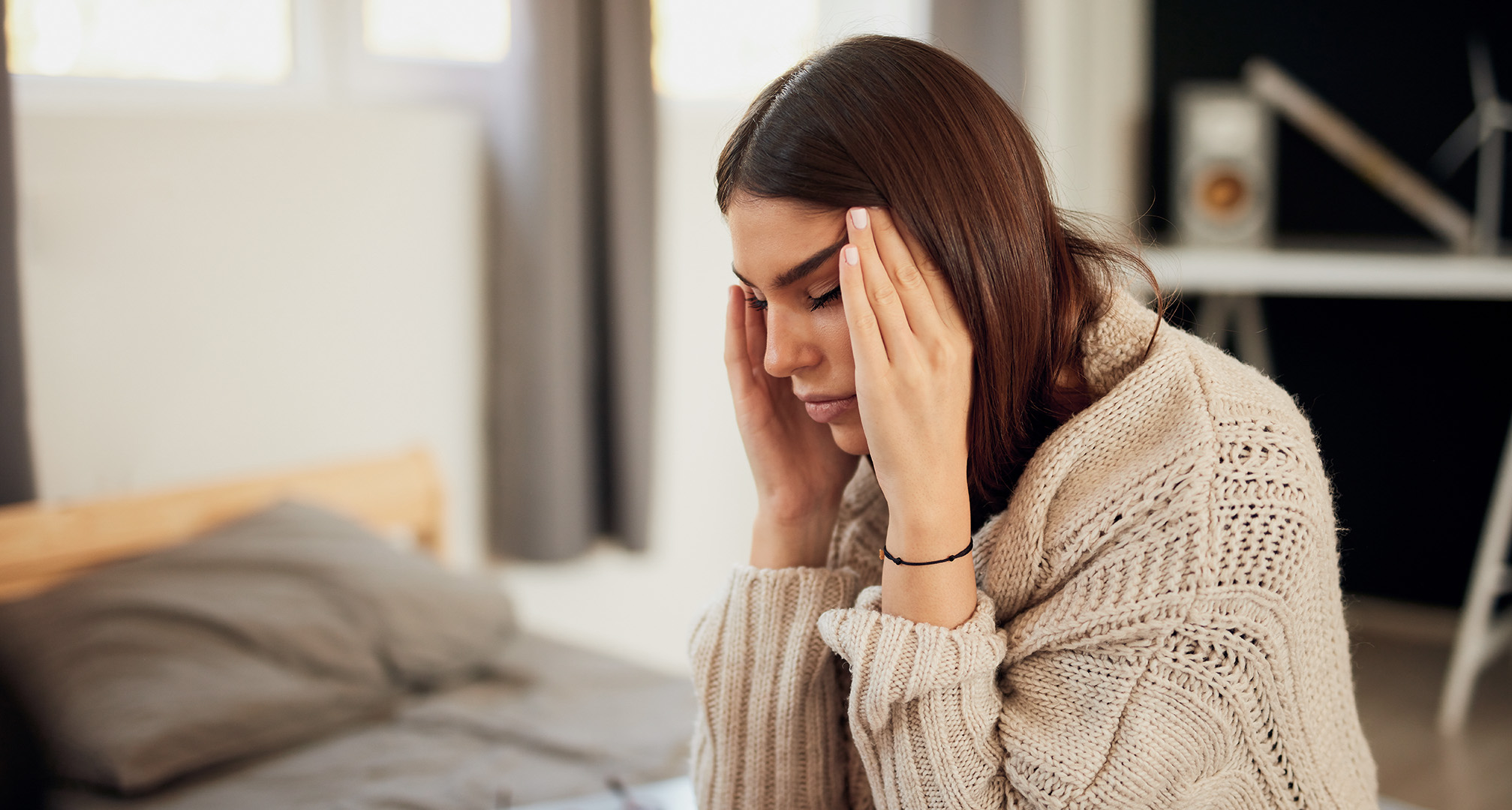 person with closed eyes holding their head