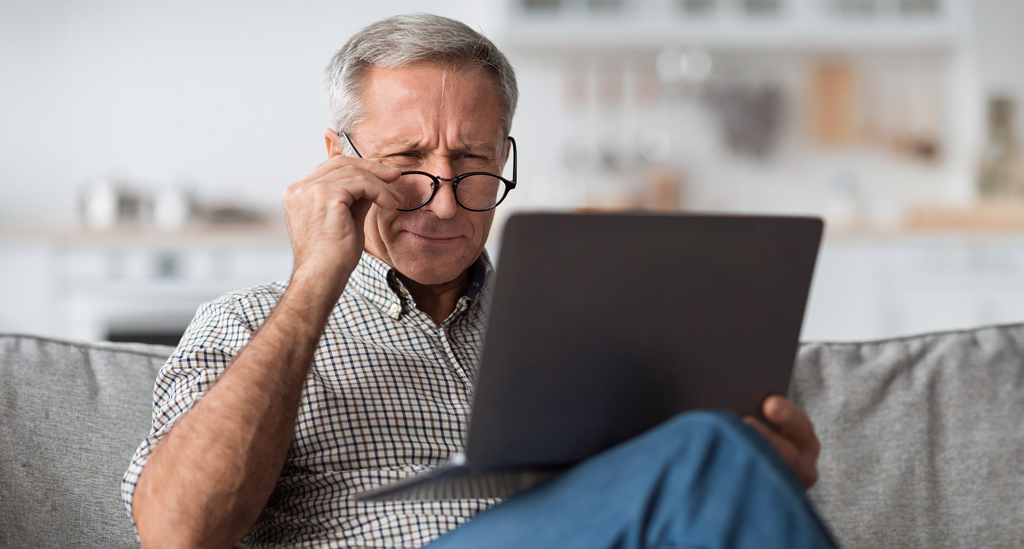person wearing glasses and squinting at laptop