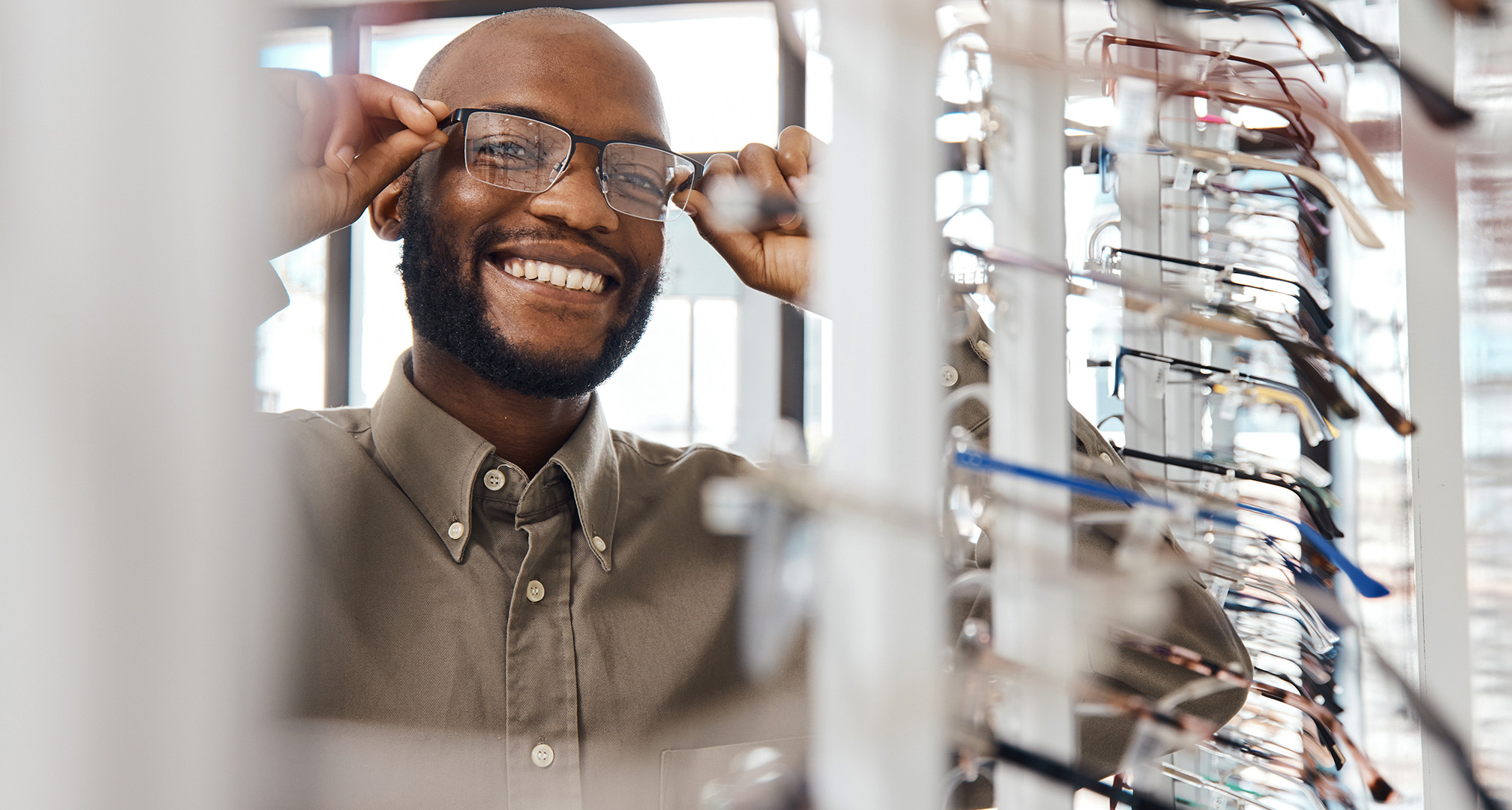 photo of smiling person trying on glasses at optician