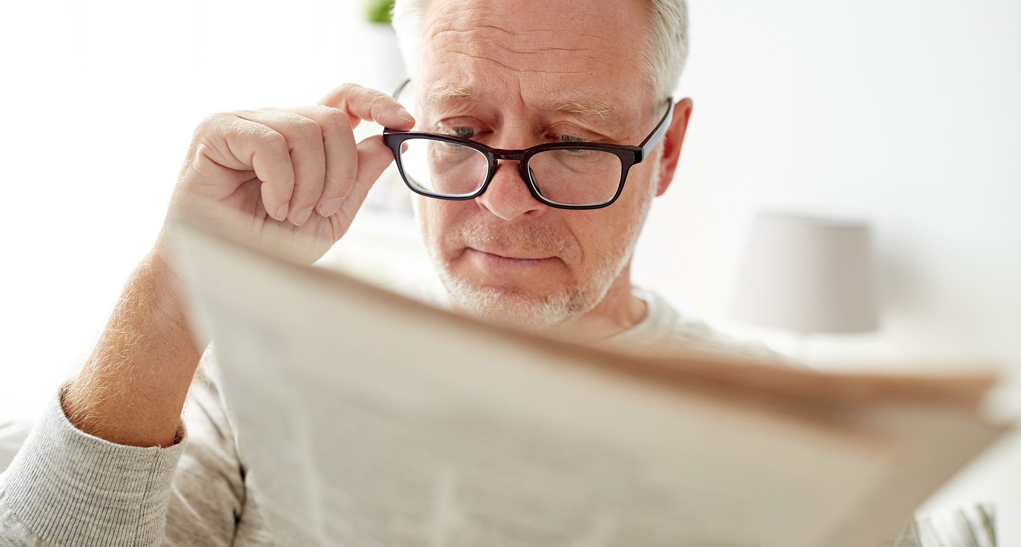 person reading and holding glasses at end of nose